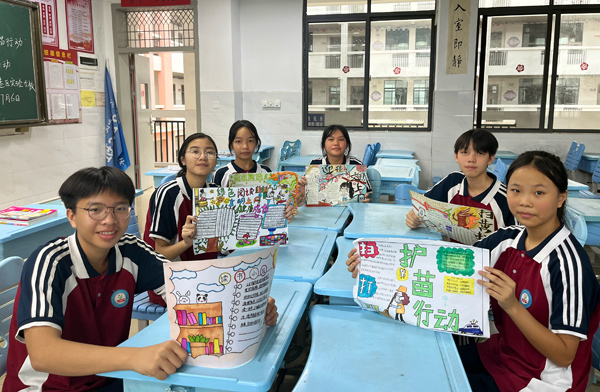 學生展示自己設(shè)計的“掃黃打非”板報作品。