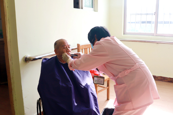 護(hù)工正在給老人刮胡子。黃穎攝