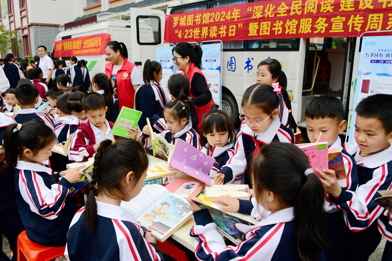 小學(xué)生在流動圖書車前閱讀圖書。