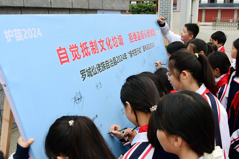 小學生在“綠書簽行動”簽名墻上簽名。