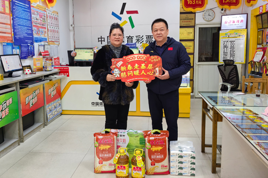 廖學(xué)志（右）為實(shí)體店代銷(xiāo)者送上米油等新春慰問(wèn)品。廣西體彩供圖