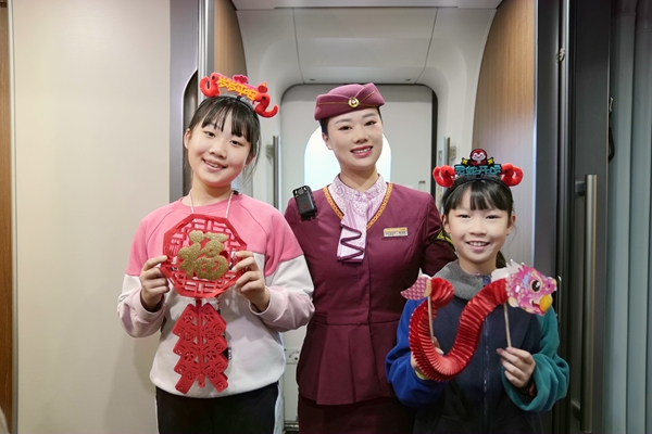 圖為列車長楊亞楠給乘車的孩子贈送福字、玩偶，并合影留念。曹爍攝