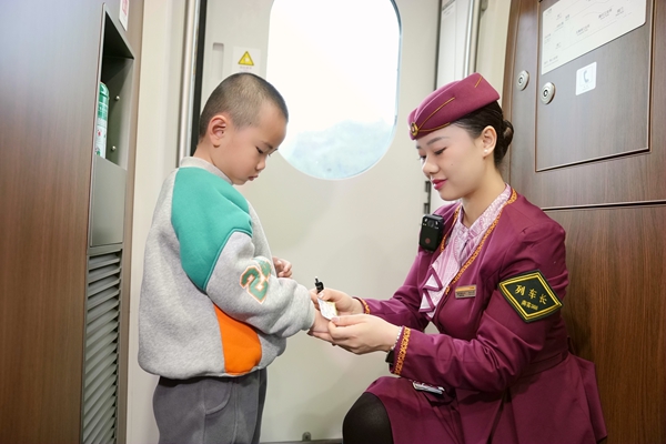 圖為列車長楊亞楠為乘車的孩子發(fā)小獎狀。曹爍攝