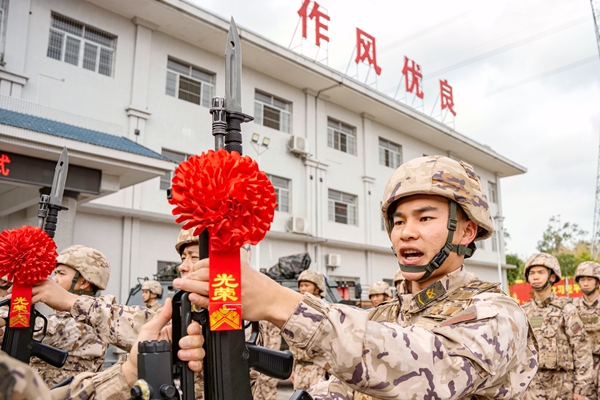 老兵將手中鋼槍交于新兵。