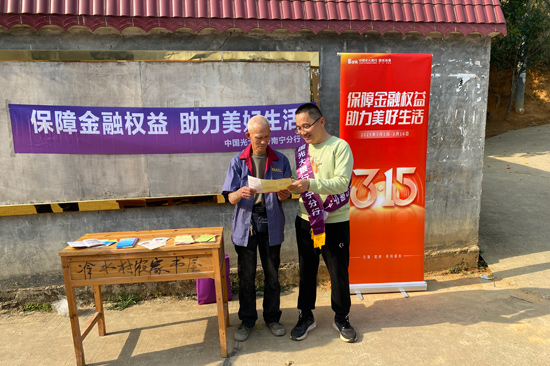 駐村第一書記主動(dòng)向過(guò)路村民發(fā)放宣傳折頁(yè)，耐心詳細(xì)講解金融知識(shí)。鐘穎攝