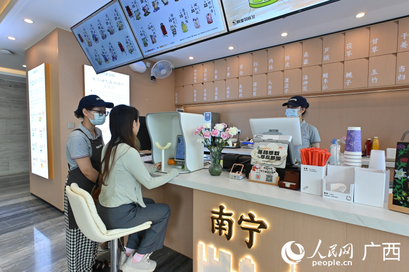 韋女士在店員的指導(dǎo)下使用AI配制中藥茶飲。人民網(wǎng) 雷琦竣攝